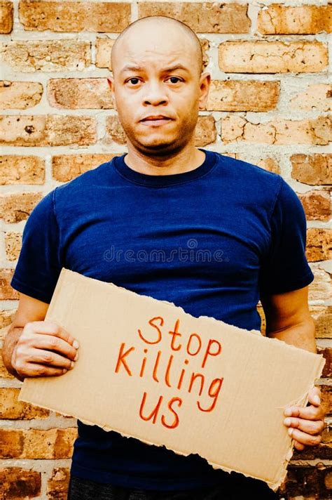 A Black Man Is Holding A Sign That Says Stop Killing Us Stock Photo