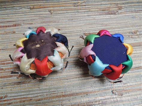 Two Chinese Silk Pin Cushions With Little Human Figures