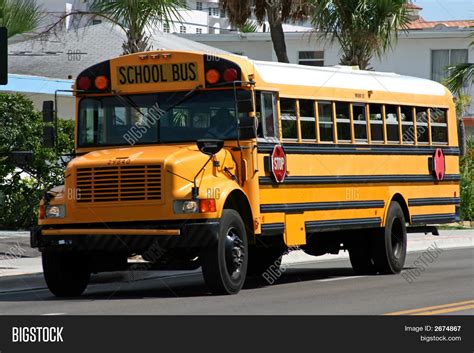 Yellow American School Bus Driving Along The Street Stock Photo And Stock