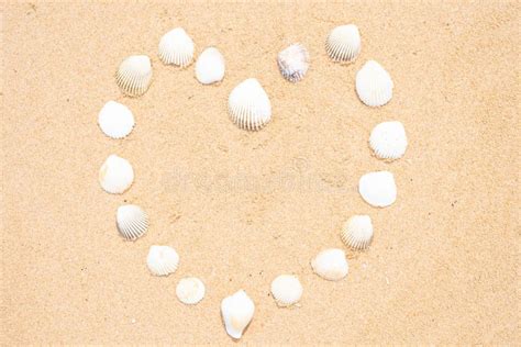 Small Seashells In The Shape Of A Heart On A Smooth Sandy Beach Stock