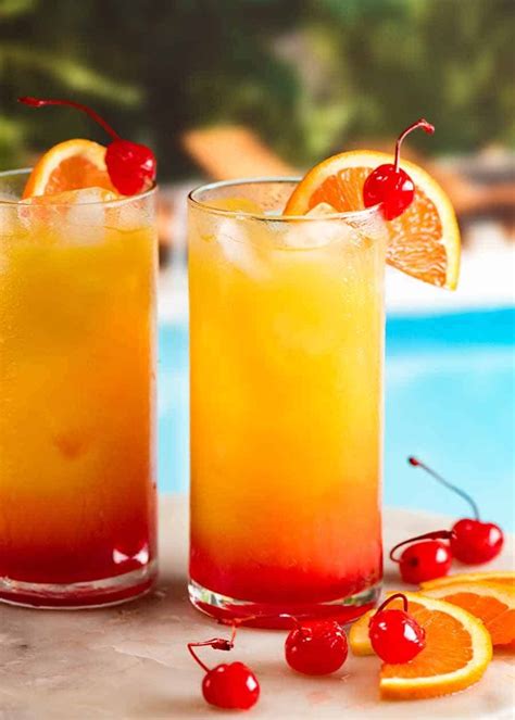 Two Tequila Sunrise Cocktails By A Pool Garnished With Orange Slice