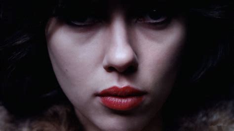 a woman with dark hair and red lipstick wearing a fur collar looking at the camera