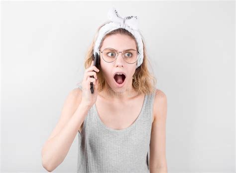 Portrait Of A Shocked Young Casual Blonde Woman Talking On Mobile Phone