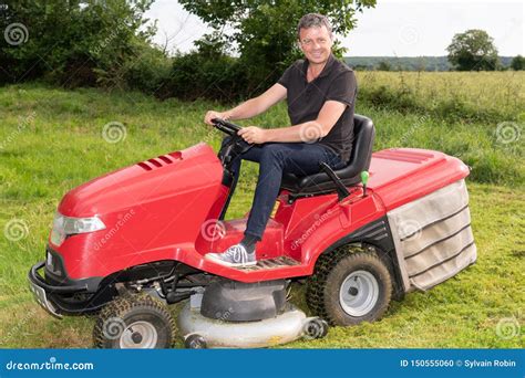 Gardner Man On Ride On Lawn Mower Gardener In Garden Stock Photo