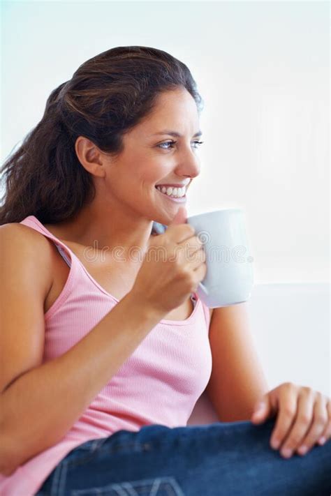 woman holding a cup and giving a cute smile woman holding a cup of coffee smiling and looking
