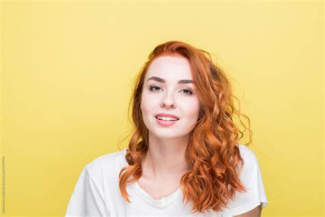 Studio Portrait Of Happy Redhead Woman Against The Yellow Background