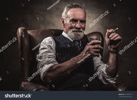 In Chair Sitting Senior Business Man With Cigar And Whisky Gray Hair