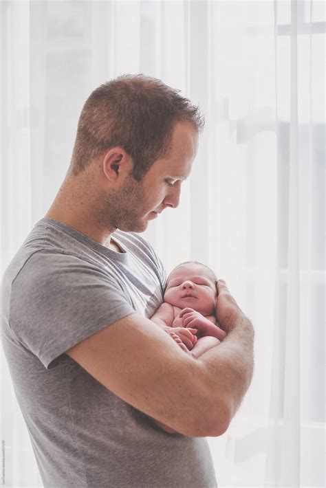 Father Holding His Newborn Son In His Arms And Looking At Him Del Colaborador De Stocksy Lea