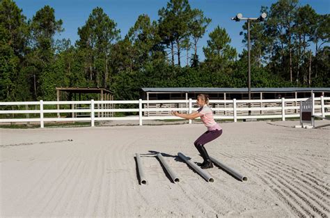 A Woman Is Jumping Over Some Skis In The Sand