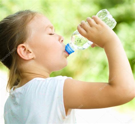 Cute Girl Drinks Water From A Plastic Bottle Stock Photo By ©julaszka