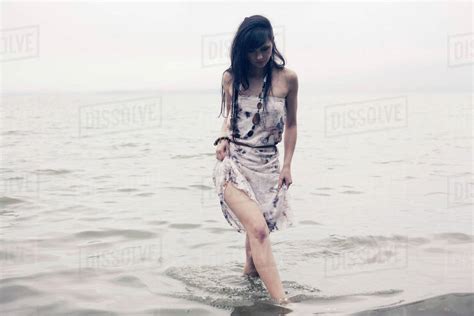 Caucasian Woman Wading In Water On Beach Stock Photo Dissolve