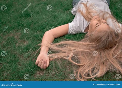 Young Natural Blonde Woman With Eyes Closed Lying In The Green Grass