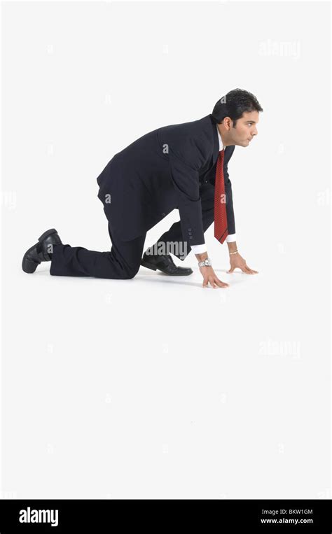 Young Businessman Kneeling In Preparation For Race Side View Stock