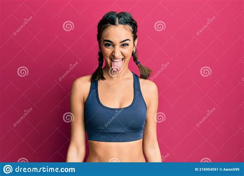 Young Brunette Girl Wearing Sportswear And Braids Sticking Tongue Out
