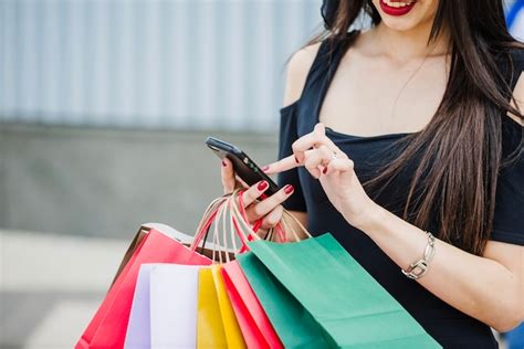 Free Photo Woman With Shopping Bags Holding Smartphone