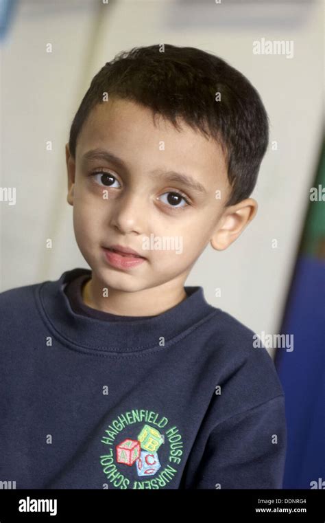 4 Year Old Boy From Pakistan Smiling Into Camera At Nursery Stock Photo