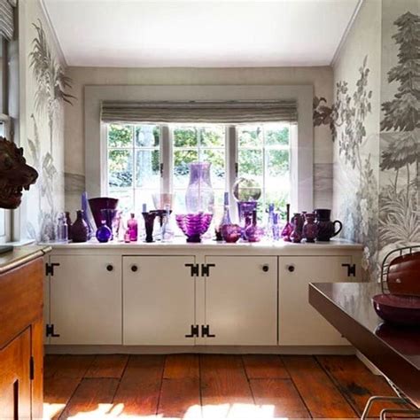 A Kitchen Filled With Lots Of Purple Vases On Top Of A Window Sill