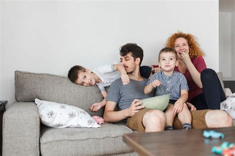 Padres Sentados Con Sus Hijos Viendo La Televisión Foto Gratis