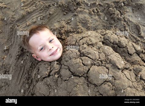 Smiling Kid Buried In Sand On Beach Of The Sea Of Azov Stock Photo