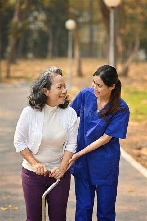 Careful Caregiver Taking Care Of Elderly Woman Patient During Walking
