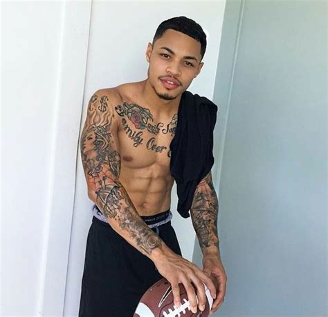 A Man With Tattoos Holding A Football