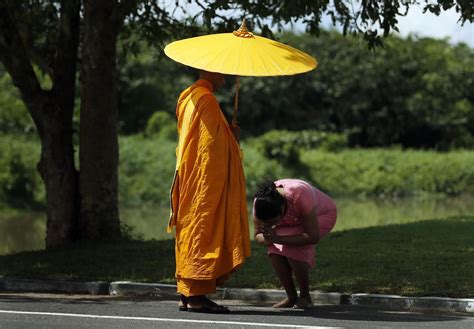 A Woman Bows In Respect To A Buddhist Monk After Offering Alms To Him