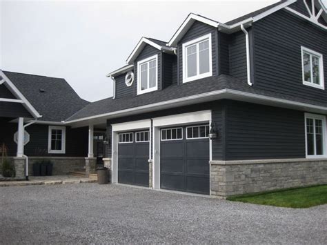 Dark blue/grey vinyl siding on a house with stone veneer around perimeter. Description from