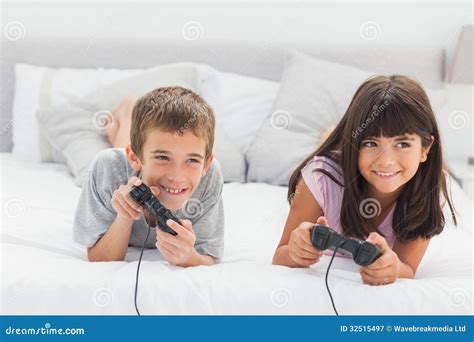Siblings Lying On Bed Playing Video Games Stock Image Image Of