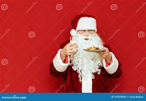 Funny Santa Claus Is Standing With Milk And Cookies In Her Hands On A