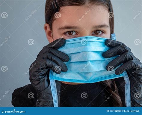 Young Girl In Black Latex Gloves Trying On A Blue Medical Facemask To