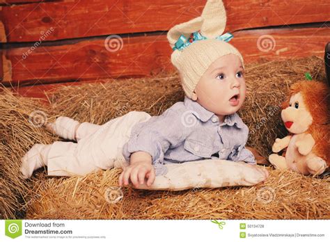 Cute Little Baby Boy In Funny Bunny Hat Lying On Straw
