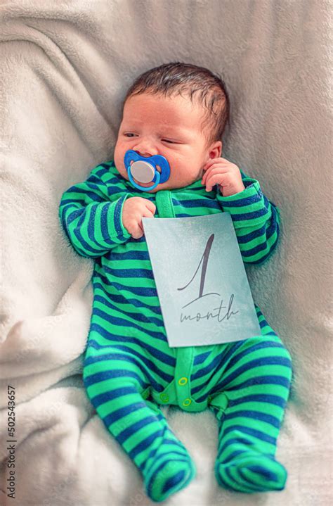 Cute Baby With 1 Month Old Milestone Card In His Hand Stock Photo