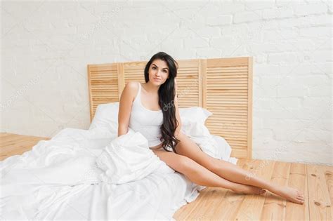 Woman Sitting On Edge Of Bed