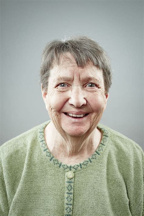 An Older Woman With Gray Hair And Green Shirt Smiling At The Camera