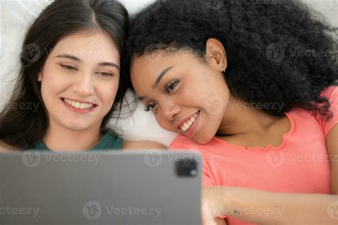 Happy Lesbian Couple Using Laptop On Bed At Home Young Multiethnic Lesbian Couple Using Laptop