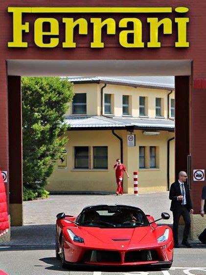 A Red Sports Car Is Parked In Front Of A Ferrari Dealership With People