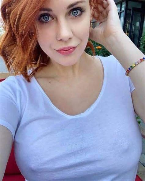 A Woman With Red Hair And Blue Eyes Is Posing For The Camera While