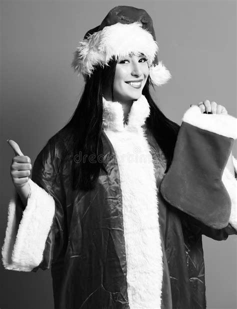 pretty cute santa girl or smiling brunette woman in red sweater and new year hat holds