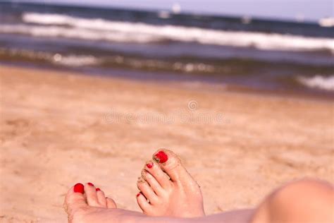 Feet Of Woman With Nails Painted Red On The Sand Of The Sea Stock Image