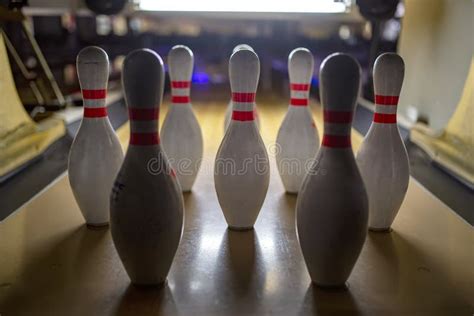 White Bowling Pins And An Orange Ball On A Bowling Alley Reflection