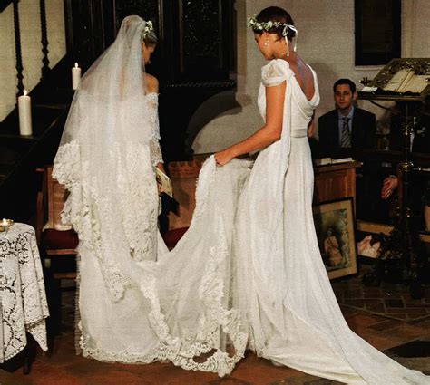 Two Women In Wedding Dresses Standing Next To Each Other Near A Table With Candles On It