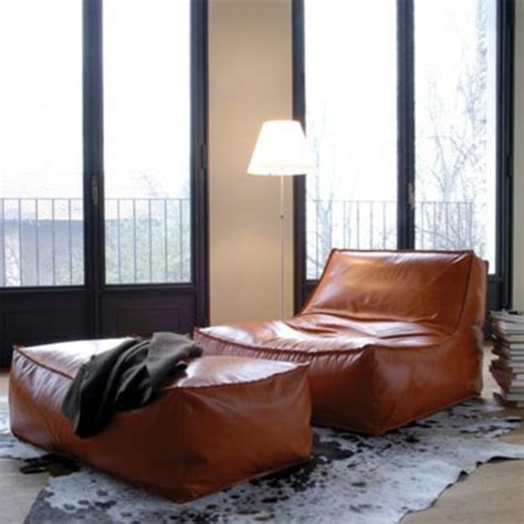 Two Brown Leather Chairs Sitting On Top Of A Rug Next To A Lamp And Window