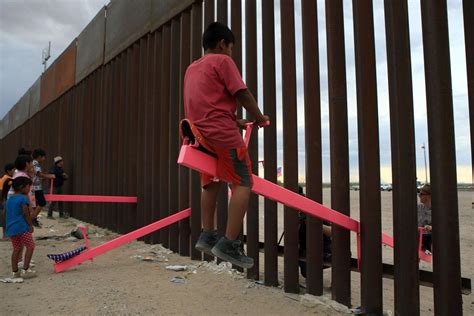 American And Mexican Families Play On Seesaws Installed Through The