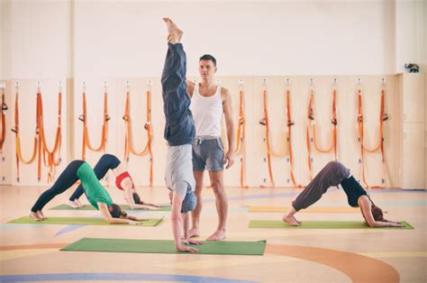 prática de yoga instrutor ajudando o aluno a fazer parada de mãos na aula adho mukha