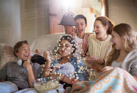 Group Of Teenagers Throwing Popcorn On Themselves While Sitting On Sofa