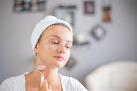 massage facial une belle femme se fait masser le visage en utilisant un rouleau facial jade