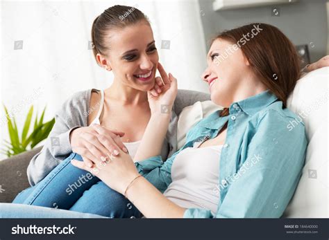 Loving Lesbian Couple Flirting And Holding Hands On The Sofa At Home