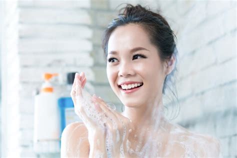 asian women are taking a shower in the bathroom she is rubbing soap she is happy and relax photo