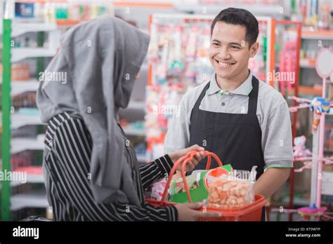 Happy Young Male Shopkeeper Or Cashier Welcoming Customer At