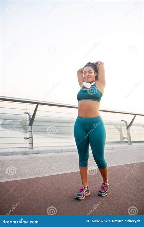 Dark Skinned Woman Wearing Leggings Stretching Before Running Stock